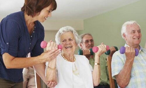 Pobl oedrannus yn ymarfer mewn cartref byw â chymorth. Elderly people exercising at assisted living home
